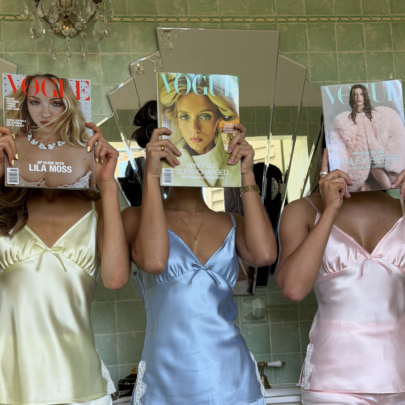 Three women holding up Vogue magazines in the LuLu sets in a vinatge bathroom. 