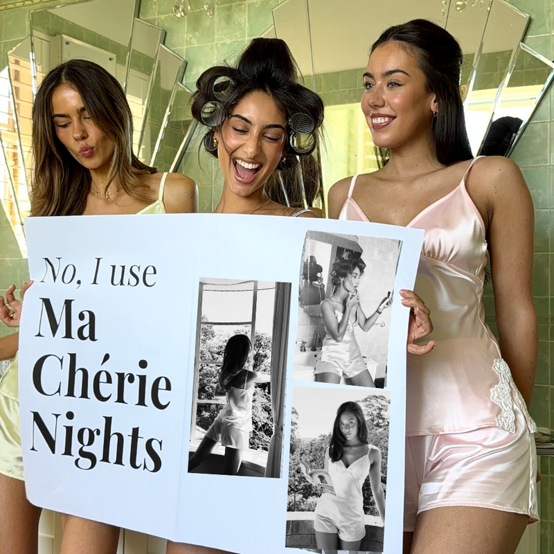 Three women in a bathroom holding a sign with 'No, I use Ma Chérie Nights' text.